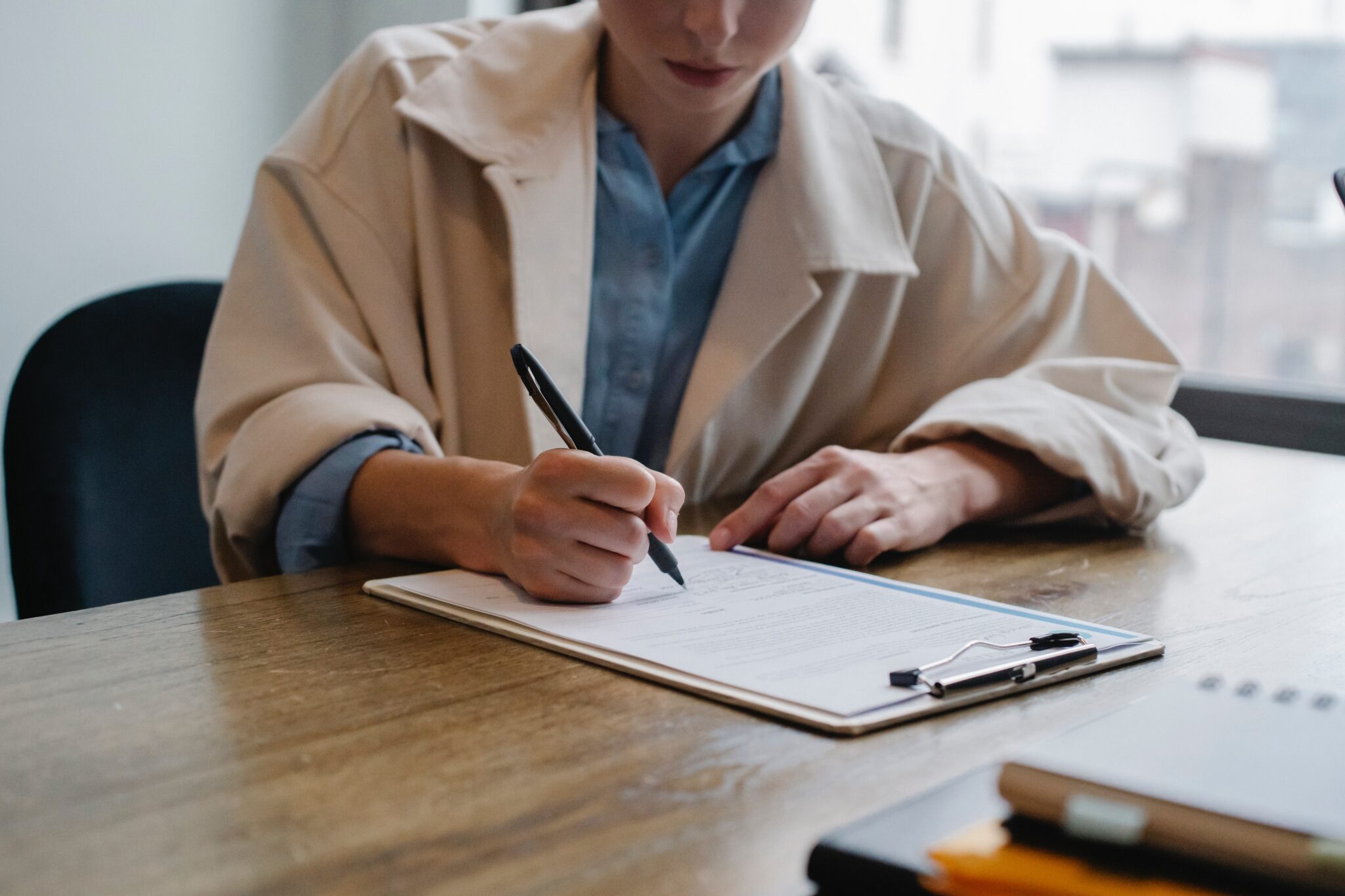 Individual sitting at a desk and filling out paper work by sora-shimazaki.